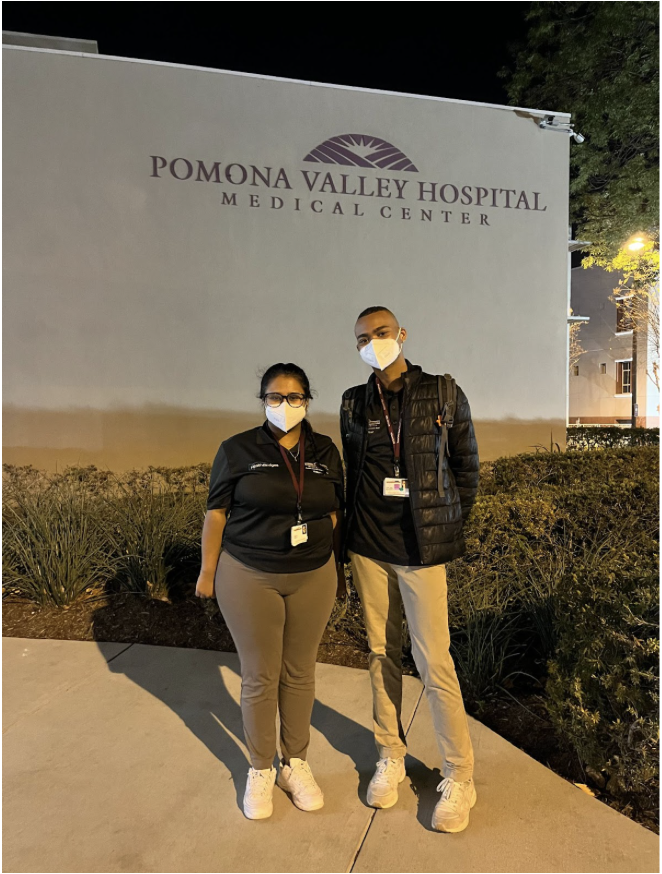 Two people standing in front of hospital sign. 