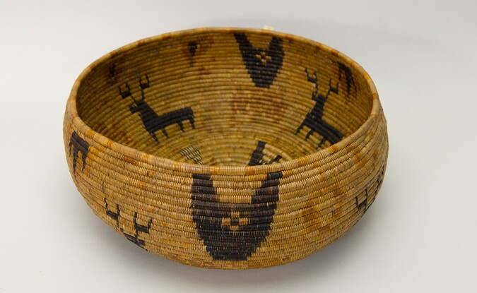 Restricted hemispherical basket with a flat base. Coiled construction. Four black deer with antlers on buff background.